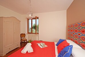 A bedroom with a bed, a wardrobe, a window, and a patterned headboard.