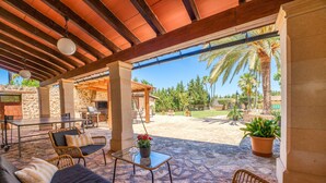 Un patio al aire libre con mobiliario de mimbre, una mesa y una planta en maceta.