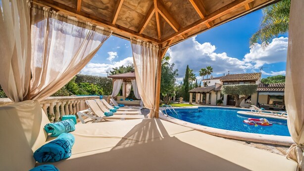 Zona junto a la piscina con sillones de descanso y vista a una alberca.