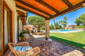 An outdoor patio with wicker furniture, a stone floor, a pool, and a covered area with a pergola.