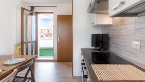 A modern kitchen with a dining area, a TV, and a view of buildings outside. - Holiday Apartment "Bella Cora" With Garden and Private Rooftop Terrace (LAZISE)