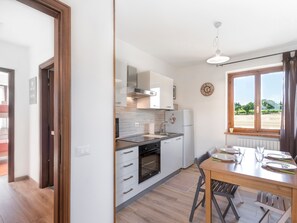 Una cucina moderna con zona pranzo, pavimento in legno e vista attraverso una finestra.