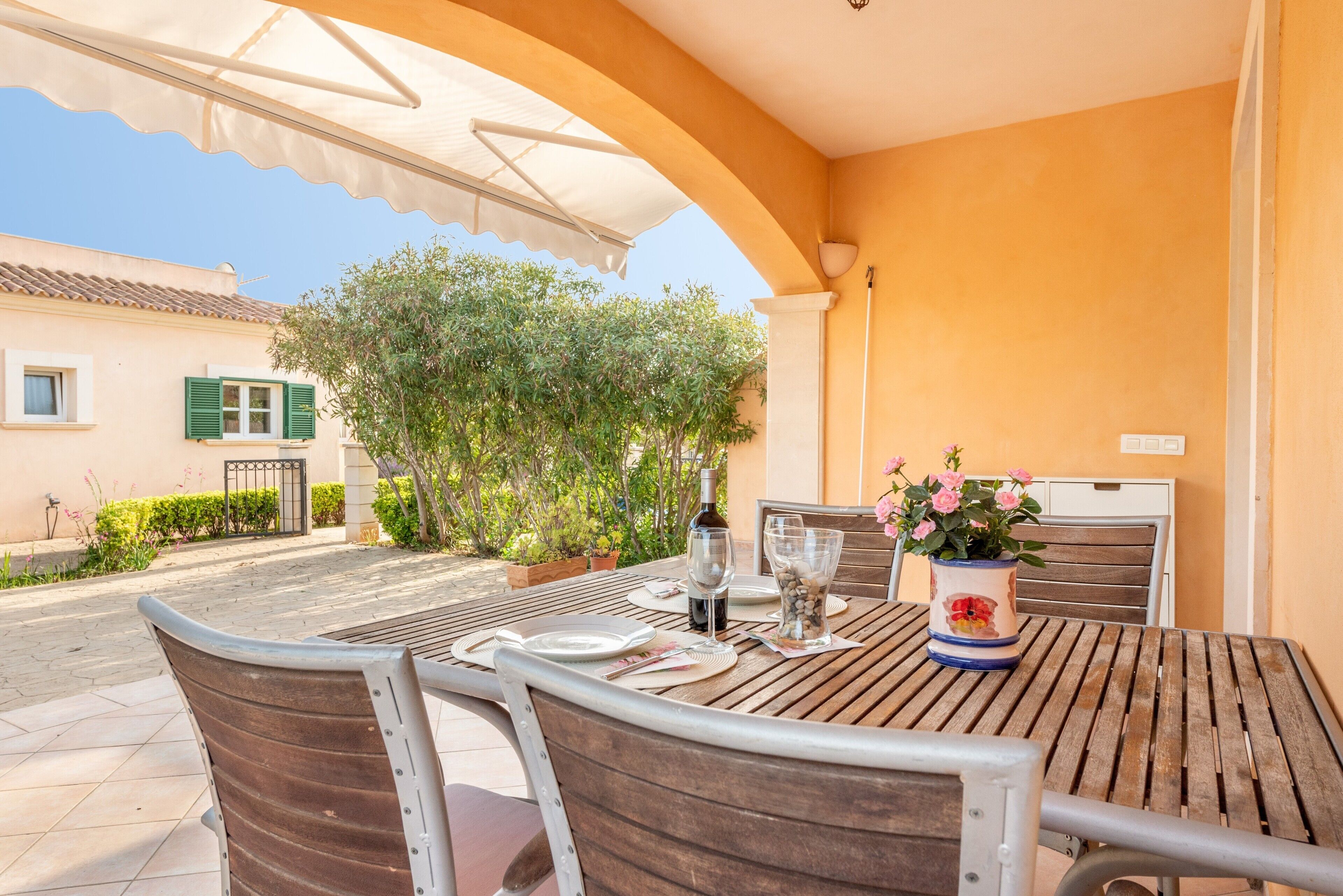 An outdoor patio with a table set for dining, chairs, and a potted plant.