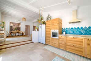 Eine moderne Küche mit Holdekor-Schränken, einem eingebauten Backofen und einer blauen Fliesenrückwand.