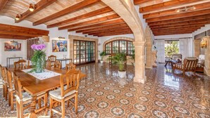 Un amplio comedor con mesas y sillas de madera, suelo de baldosas y un alto techo de madera con vigas a la vista.
