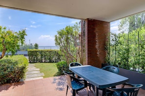 Un patio con mesa y sillas, un muro de ladrillo y vista al mar.