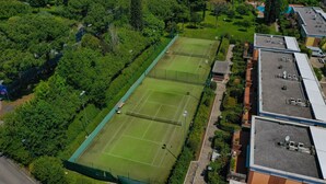 Luftaufnahme eines Tennisplatzes, umgeben von Bäumen und Gebäuden.