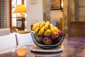 A bowl of fruit on a table with a lamp in the background.