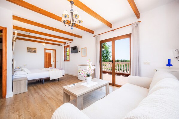 Une pièce avec des poutres en bois, un lit, un canapé, une table avec un vase et un balcon doté d’une balustrade.
