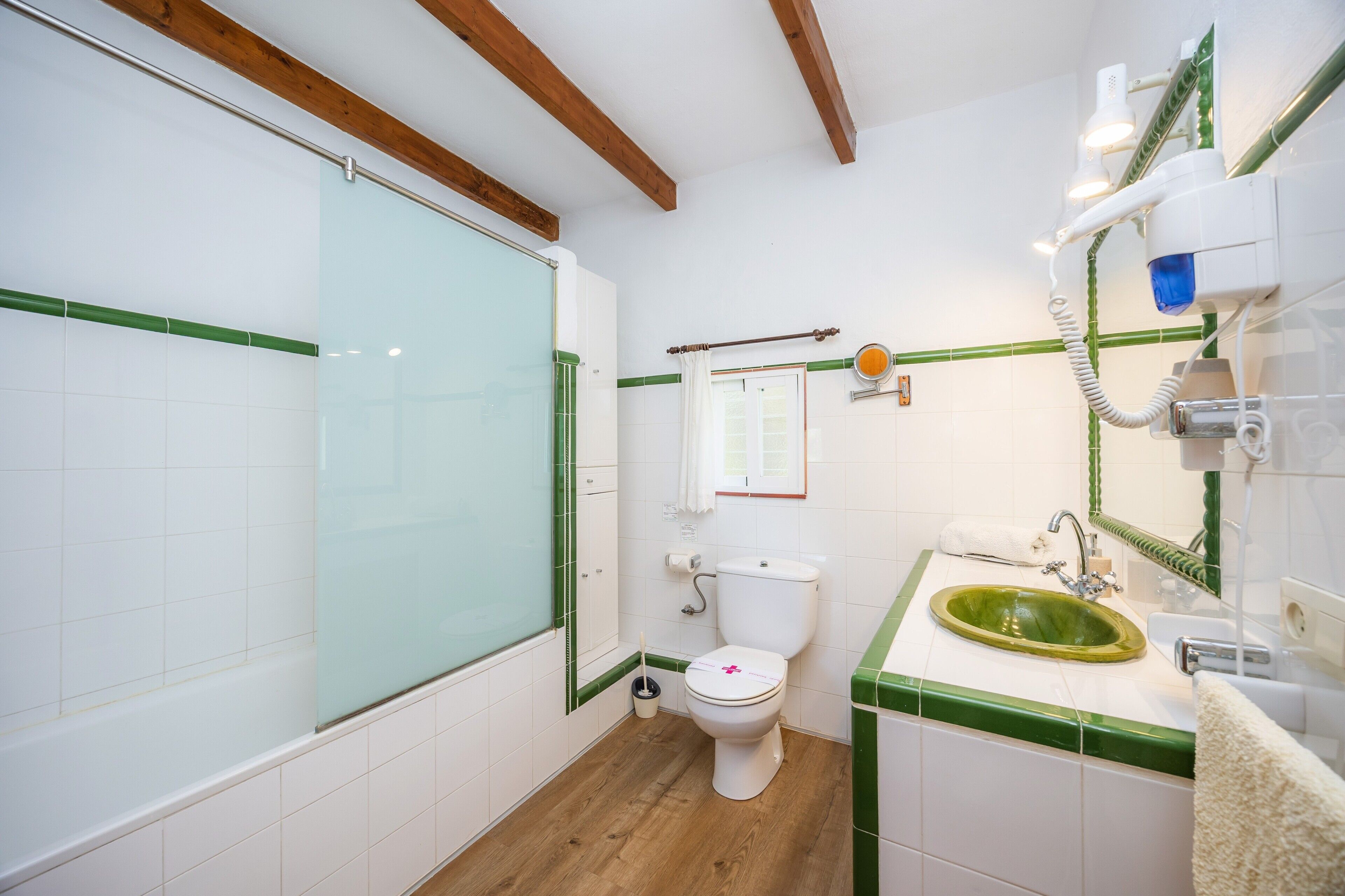 Een badkamer met douche, toilet, wastafel en spiegel.