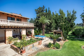 A house with a balcony, a pool, and a garden with various plants.