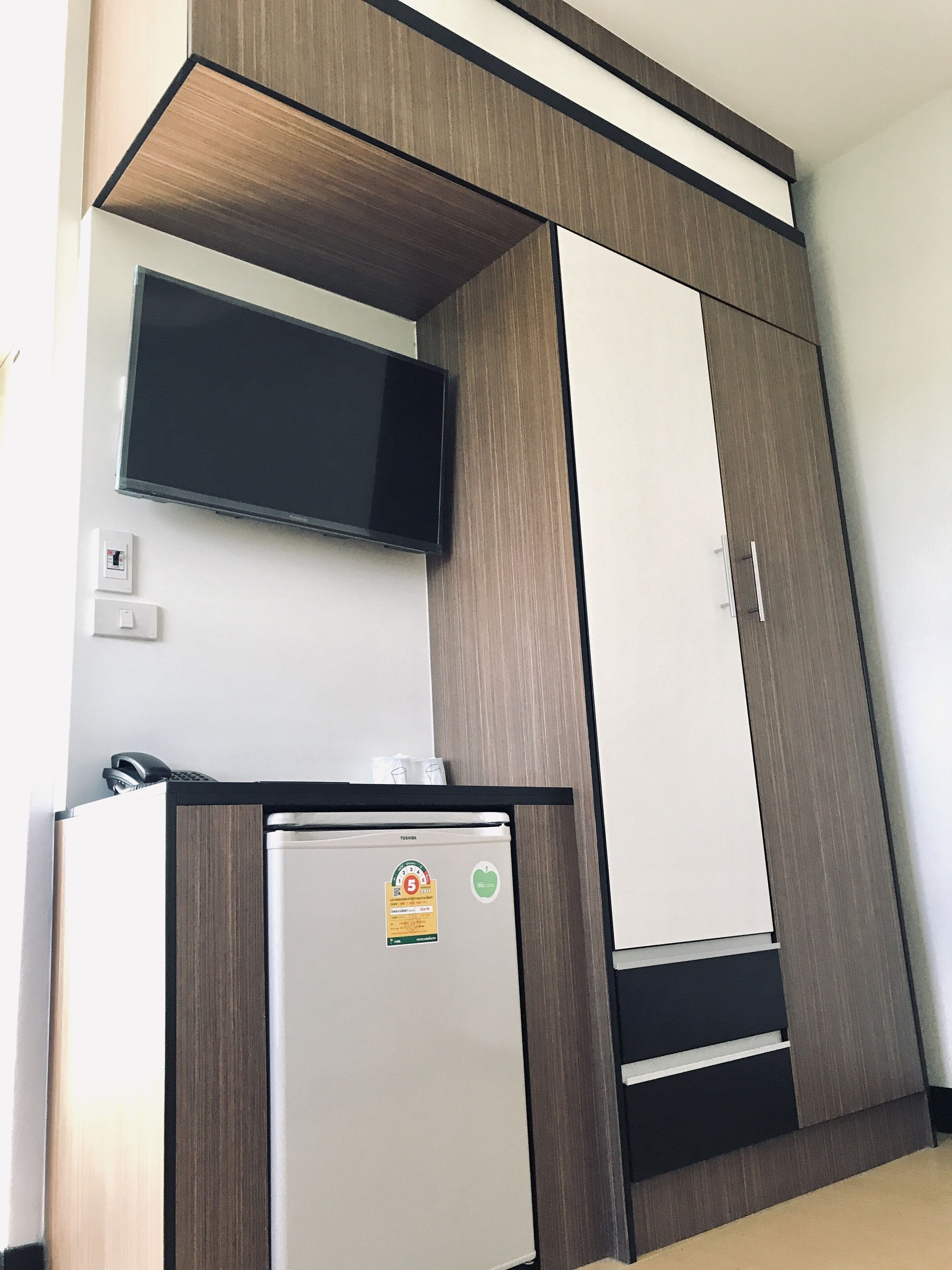 A kitchenette with a refrigerator, a microwave, and a flat-screen TV mounted on the wall.