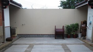 A courtyard with a tiled floor, a wooden chair, potted plants, and a door with a bicycle drawing. - I Like B&B (Jinsha)