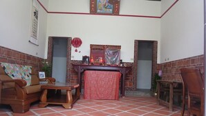 A room with a tiled floor, a wooden sofa, a wooden table, and a red curtain. - I Like B&B (Jinsha)