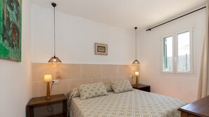 Un dormitorio con una cama, dos mesitas de noche, un cuadro en la pared y una ventana.