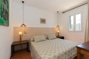 A bedroom with a bed, two bedside tables, a wall-mounted picture, and a window.