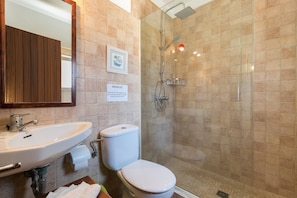 Une salle de bain équipée d’un lavabo, de toilettes et d’une douche à parois de verre.