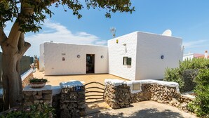 Un edificio blanco con entrada de pared de piedra, una antena parabólica y un ventanal pequeño.