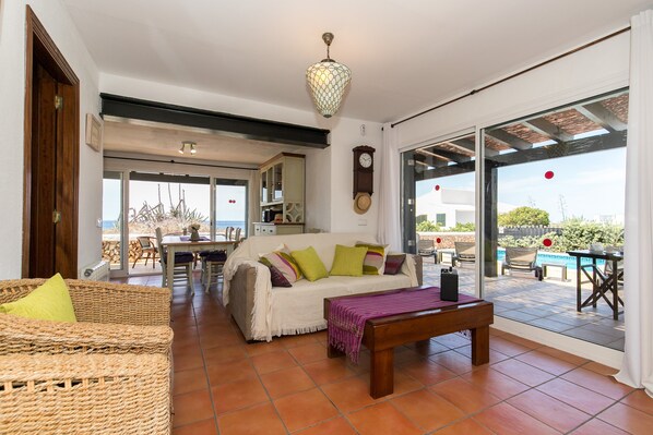 A spacious living room with a sofa, a bench, and a dining area with chairs and a table.