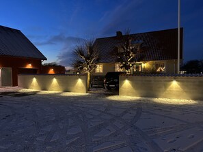 A residential area with a snow-covered driveway, a wall with lights, and a house with a tiled roof. - Halmstad Gårdshotell (Halmstad)