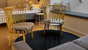 A cozy loft bedroom with a skylight, a bed, a desk, and two chairs. - Halmstad Gårdshotell (Halmstad)