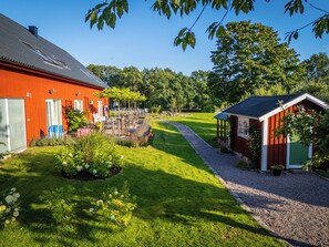 A red building with a covered outdoor area, a gravel path, and a green lawn. - Halmstad Gårdshotell (Halmstad)