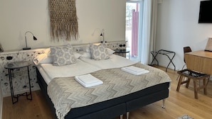 A modern bedroom with a large bed, a desk, and a chair. - Halmstad Gårdshotell (Halmstad)