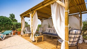 Une terrasse en bois avec un auvent, un canapé, une chaise et une table.