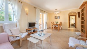 Amplia sala de estar con televisor, asientos y una mesa de comedor.
