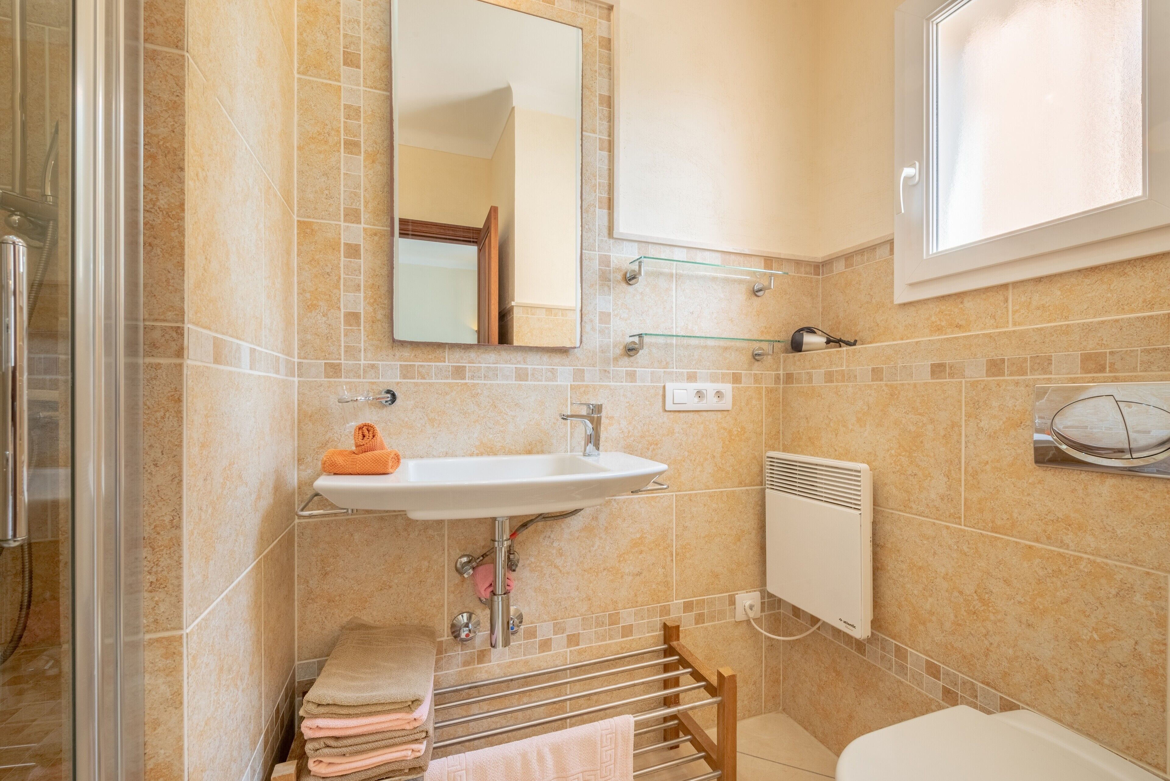 A bathroom with a sink, mirror, towel rack, and a window.