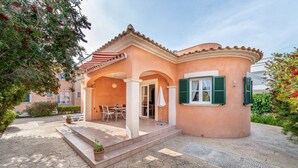Una casa con fachada curva, un patio con mobiliario exterior y un acceso cubierto.