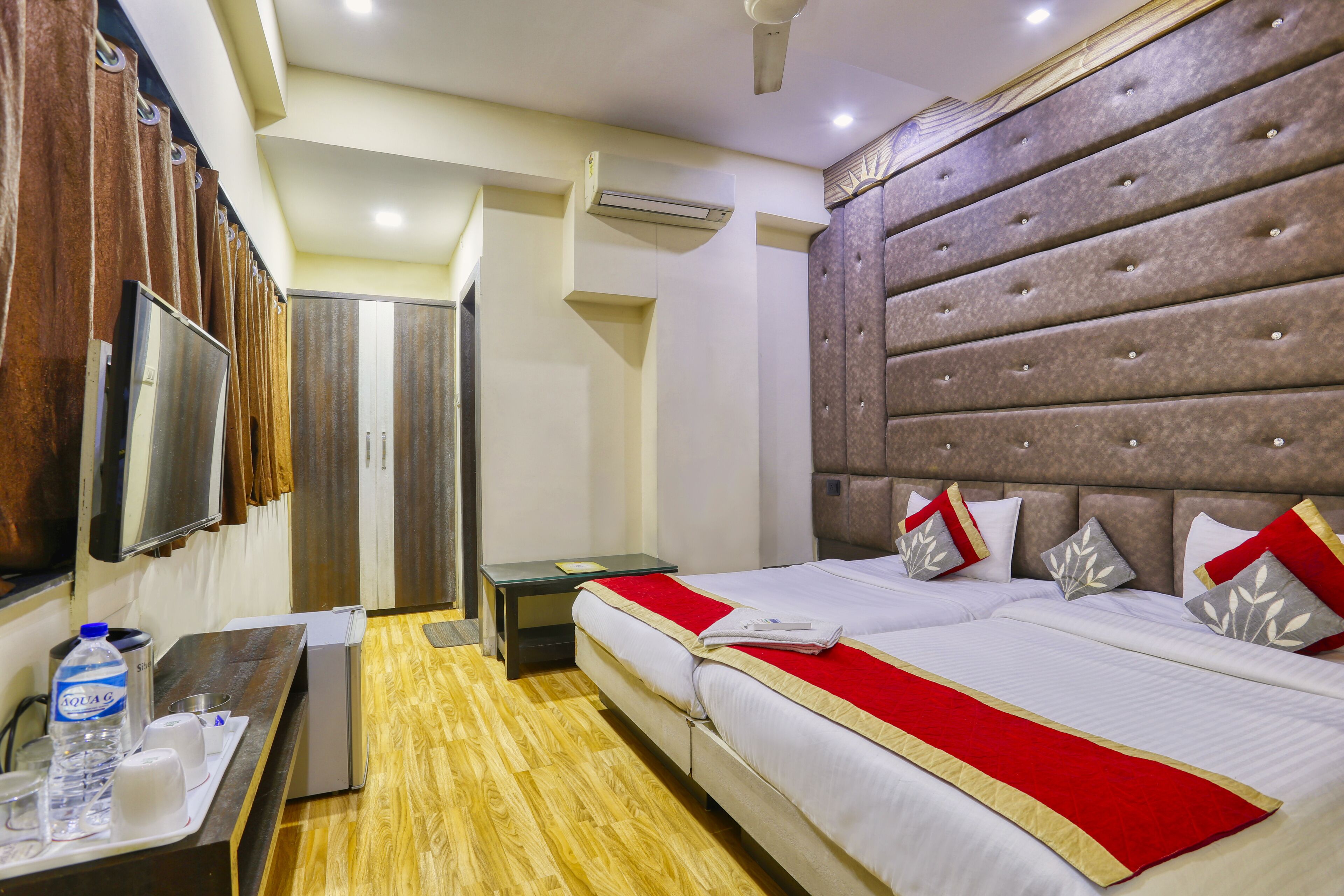 A hotel room with a large bed, a bedside table, a TV, and a wardrobe.