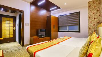 A hotel room with a bed, a television, a wardrobe, and a window with blinds.
