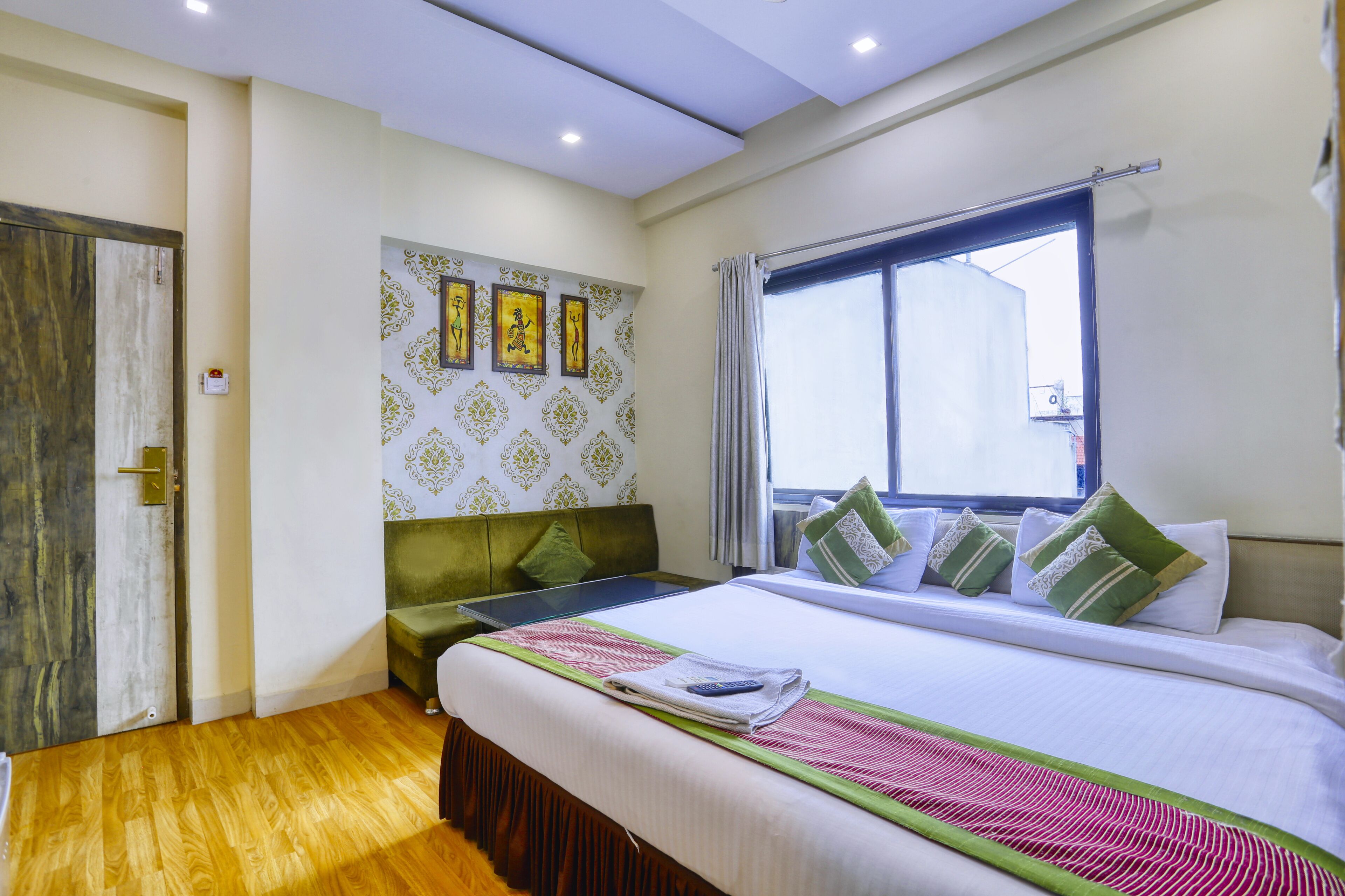 Una habitación de hotel con cama, sofá, ventana y una pared decorada con cuadros.