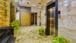A lobby with a marble floor, an elevator, and a staircase. - The Ashoka Hotel (Indore)