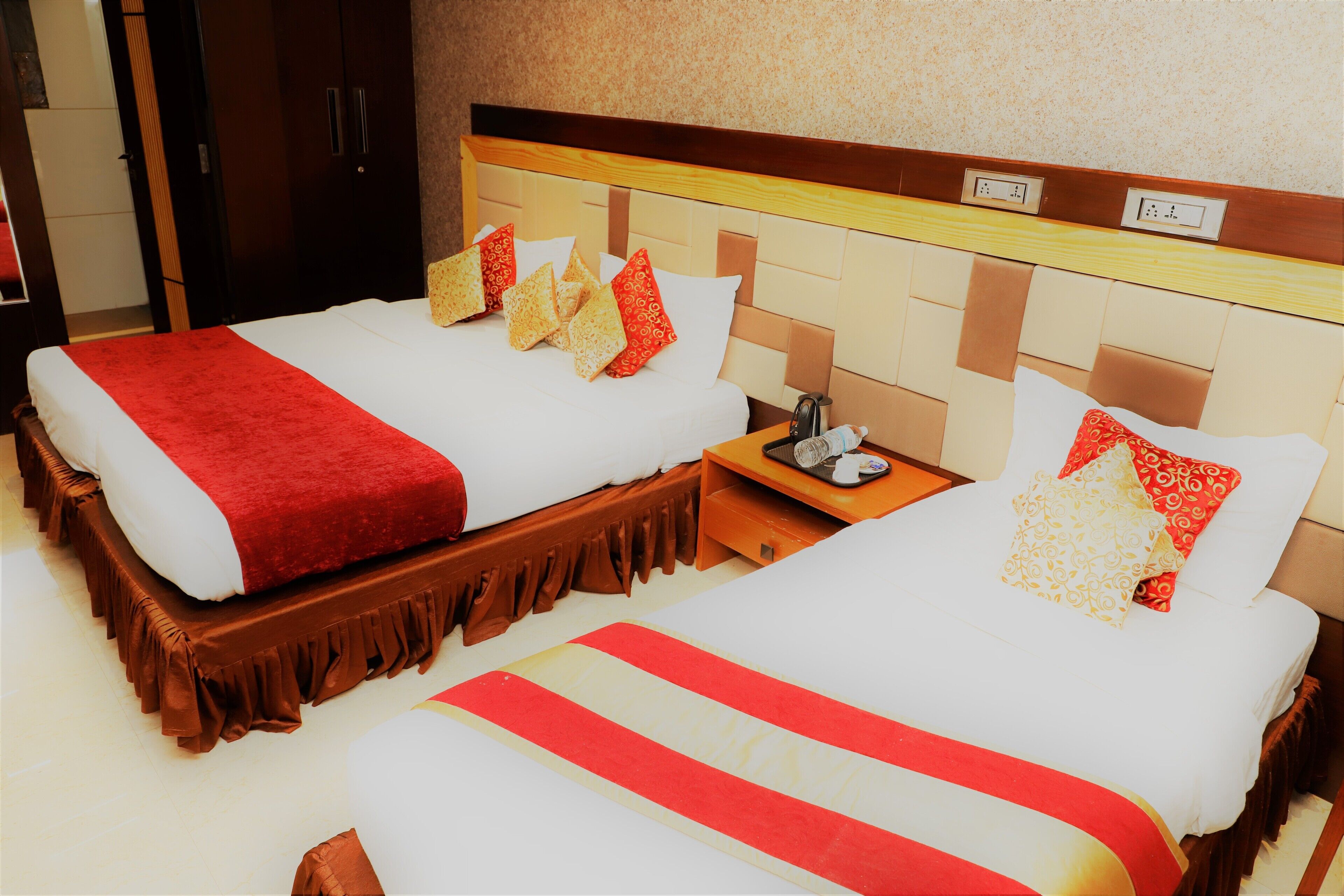 A hotel room with two beds, each with a red and white bedspread, and matching pillows.