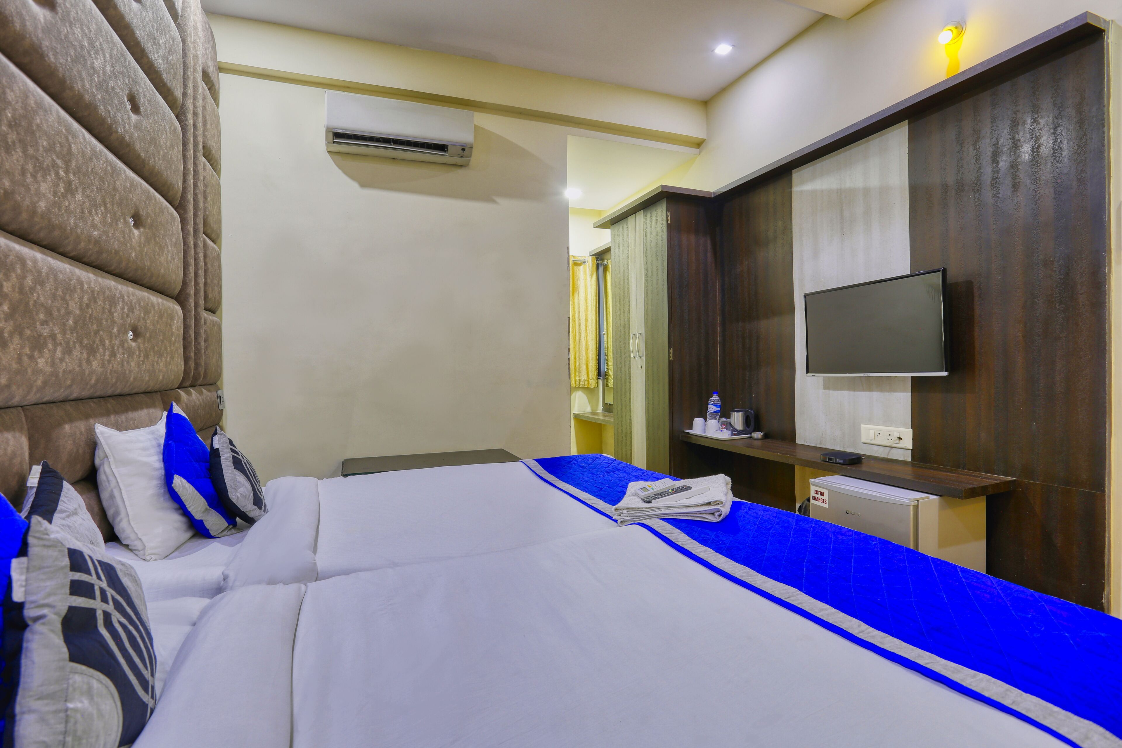 Hotelkamer met een groot bed, een flatscreen televisie, een kleine koelkast en een houten garderobe.