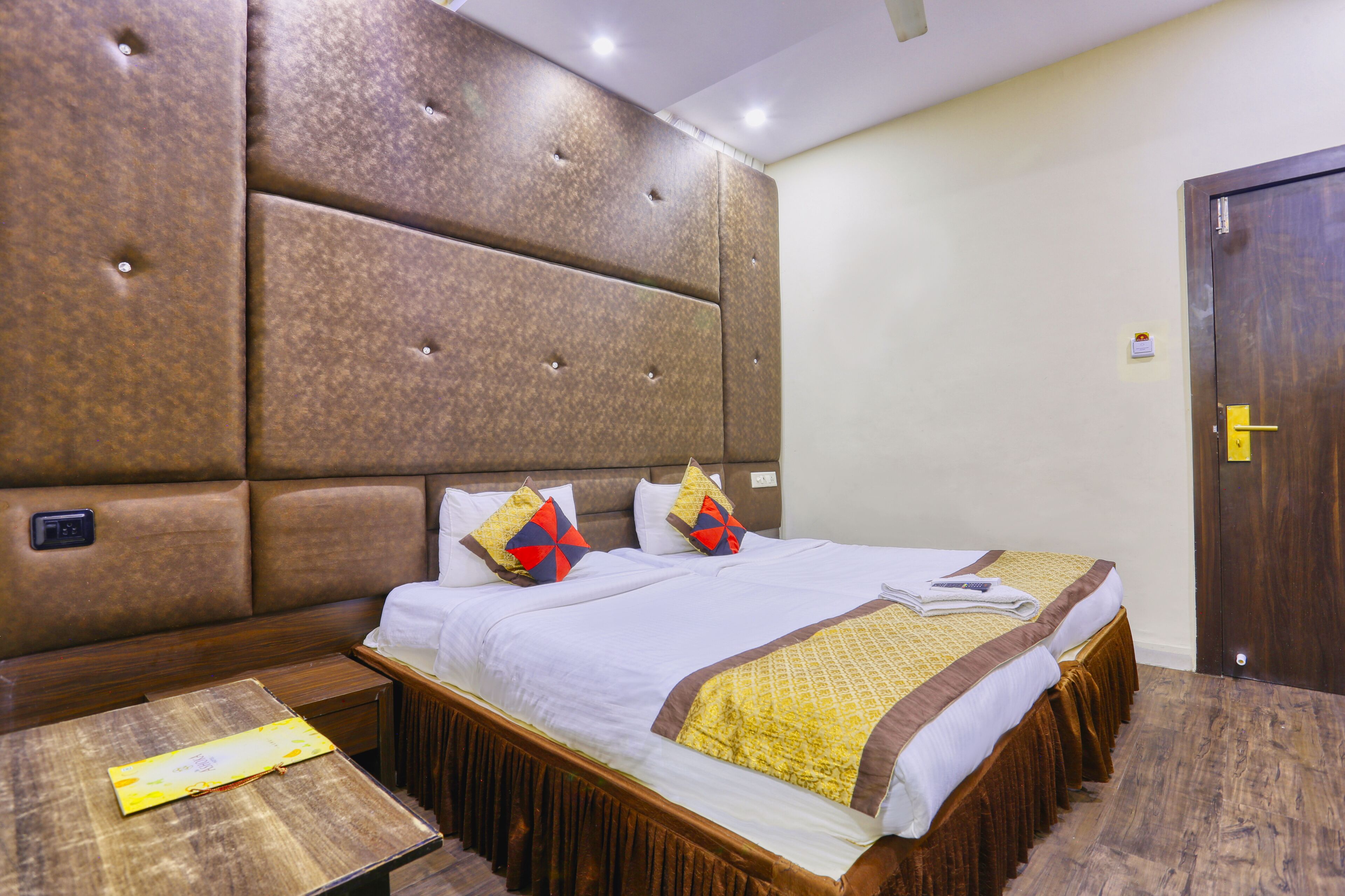 A hotel room with a large bed, a wooden nightstand, and a door.