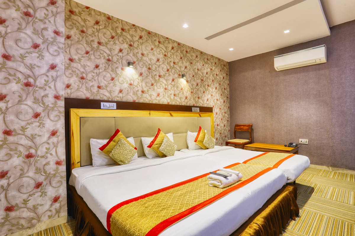 Una habitación de hotel con una cama grande, un cabecero de madera, una mesita de noche y un equipo de aire acondicionado.