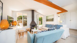 Un salón moderno con chimenea, muebles blancos y vistas al exterior.