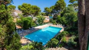 Una piscina con sillas de descanso, rodeada de árboles y vistas a edificios.