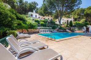 A pool area with lounge chairs, a swimming pool, and buildings in the background. - Beautiful "Can Botana 7" with Wi-Fi, Pool, Air Conditioning, Balcony and Garden (Cala Sant Vicenç)