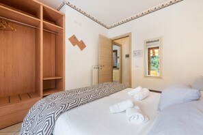 Une chambre d’hôtel avec un lit, une armoire en bois, un miroir et une fenêtre donnant sur un paysage agréable.