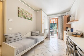Une pièce comprenant un canapé, une table à manger avec des chaises, un radiateur et une fenêtre avec des rideaux.