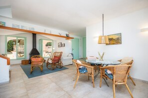 A dining area with wicker chairs, a round table, and a hanging lamp.