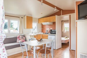 A compact kitchen with a dining area, a sofa, and a television.