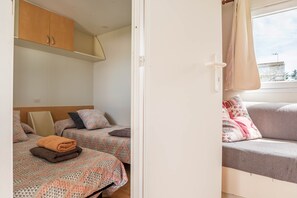Une chambre avec deux lits, un canapé et une fenêtre avec des rideaux.