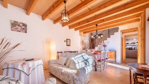 A cozy living room with a sofa, a table with a remote, and a staircase leading to a kitchen. - Charming Holiday Home Can Bonjesus with Mountain View, Wi-Fi, Garden & Terrace; Parking Available, Pets Allowed (Felanitx)
