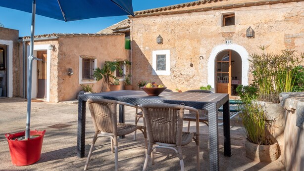 An outdoor patio with a table and chairs, a red bucket, and potted plants. - Charming Holiday Home Can Bonjesus with Mountain View, Wi-Fi, Garden & Terrace; Parking Available, Pets Allowed (Felanitx)