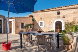 An outdoor patio with a table and chairs, a red bucket, and potted plants.